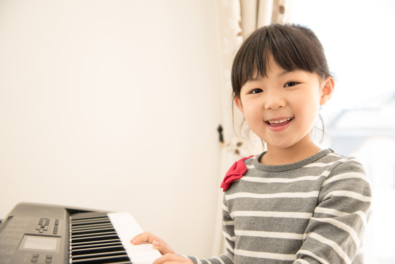 ピアノを弾いて微笑む女の子の写真