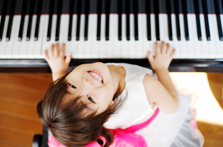ピアノを弾きながら見上げる女の子の写真