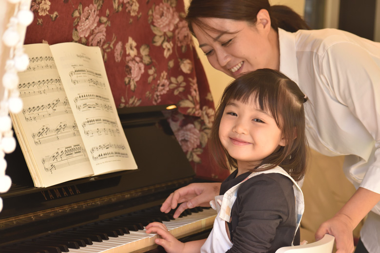 ピアノを弾きながら振り向いて微笑む幼児の女の子の写真